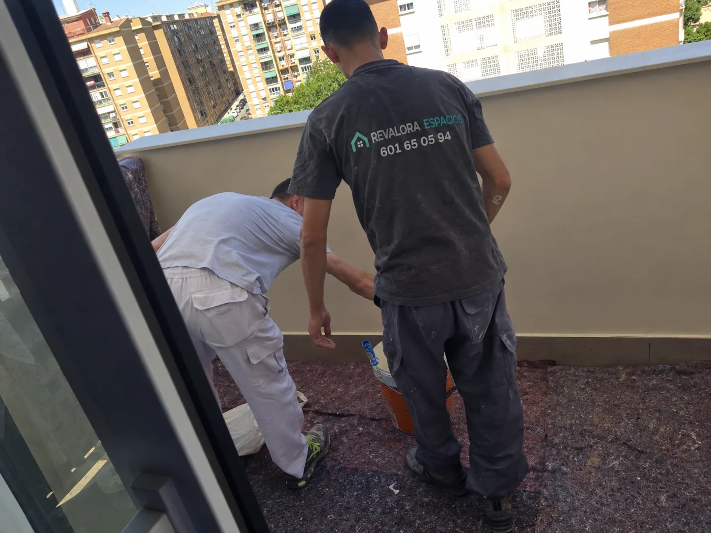 Dos trabajadores de REVALORA preparando una zona exterior de terraza durante una intervención en un inmueble.
