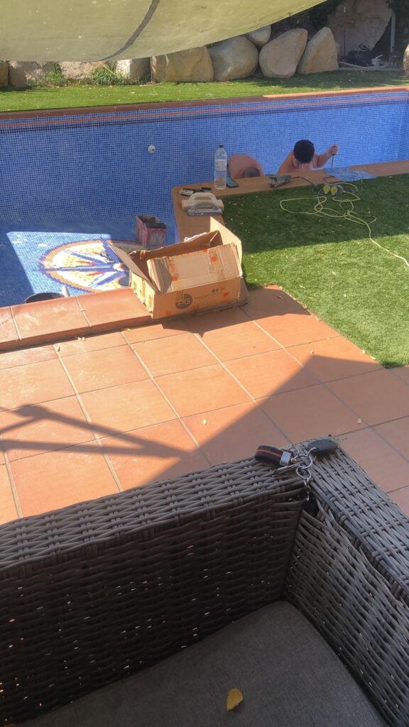 Operarios trabajando en la piscina vaciada durante la reparación de las juntas.